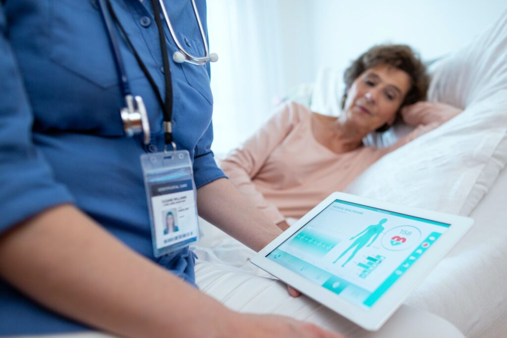 Digital Tablet Showing Test Results of Elderly Female Patient Lying in Bed in the Background.